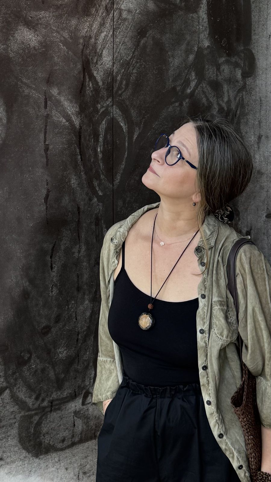 Magdalena Wangrat patrzy w górę, oparta o ciemną, fakturową ścianę